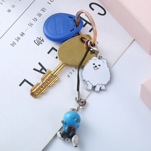 Detail shot of golden metal key chain with white Pomeranian enamel dog charm
