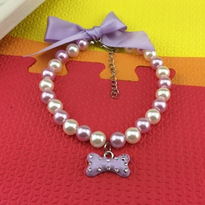 Detailed macro view of purple bone pendant and satin bow on pearl pet necklace