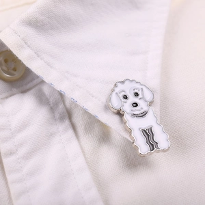 Gros plan d'une broche caniche en émail blanc épinglée sur le col d'une chemise blanche