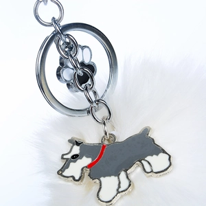 Détail du porte-clés Schnauzer avec pompon en fourrure blanche et charme empreinte de patte