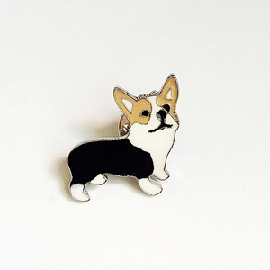 Détail d'un pin's en émail Corgi avec couleurs noir, blanc et jaune sur base métal