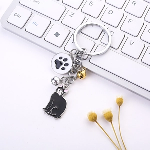 Close-up of black cat keychain with small bells and paw charm on office desk