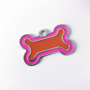 Close-up of bone-shaped metal pet ID tag with pink and orange enamel and hanging hole