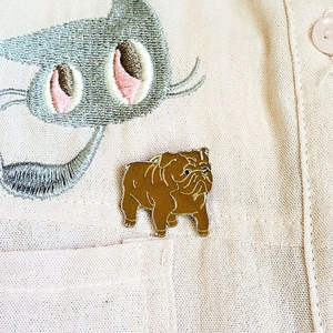 Gros plan détaillé d'une broche bouledogue en émail marron sur une poche de chemise