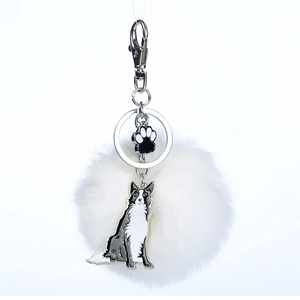 Détail d'un pompon en peluche avec pendentifs en métal de Border Collie et patte