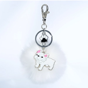 Détail du porte-clés pompon blanc avec patte de chien et charms émaillés de bouledogue