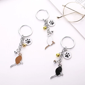 Three colorful cat keychains with double bells and paw charms on white background