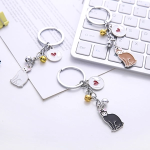 Three colorful metal cat keychains with gold bells and I love cat charms on a desk