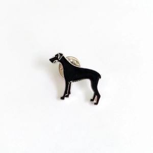 Vue détaillée d'une broche chien en émail noir avec bords en argent et attache papillon