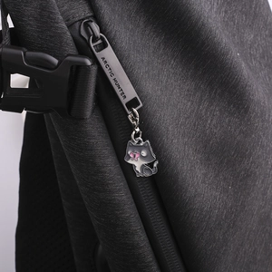 Close-up of black textured backpack with Arctic Hunter zipper and colorful cat pendant