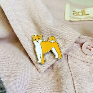 Gros plan d'une broche en émail Shiba Inu portée sur un col de chemise rose