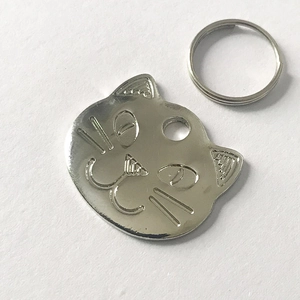 Detailed macro view of silver cat-shaped metal pet ID tag with engraved face and split ring