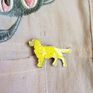 Détail d'une broche émaillée en forme de labrador jaune sur une poche