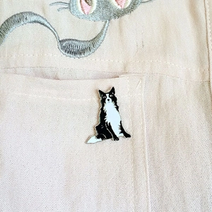 Détail d'une épingle émaillée Border Collie fixée sur une poche en tissu beige