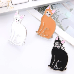 Trois jolies broches chat en émail assis en blanc orange et noir sur bureau