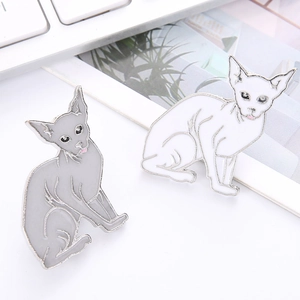 Broches en émail chat Sphynx gris et blanc présentées sur un bureau style minimaliste