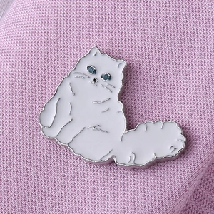 Détail de la broche chat en émail blanc aux yeux bleus sur tricot rose tendre