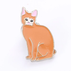Détail d'une broche chat en émail orange avec bords en métal poli et finition brillante