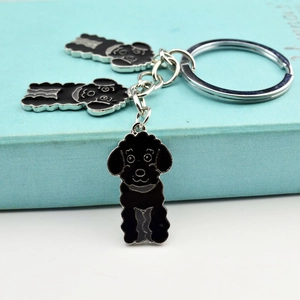 Detail of cute black poodle enamel keychains with silver metal rings on a blue box