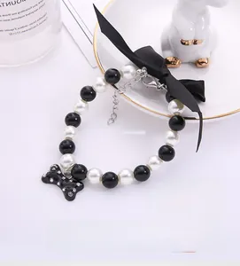 Detailed shot of black and white pearl pet collar with a bow and rhinestone bone pendant
