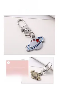 Detail of creative Saturn shaped metal keychain with red and blue enamel and antique bronze finish