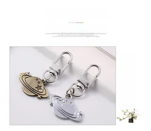 Detail of creative Saturn planet couple keychains in antique bronze and silver finish