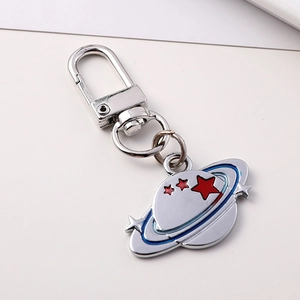 Metallic Saturn planet keychain with red stars and blue enamel ring in a 45-degree angle view