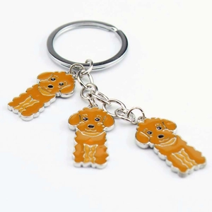 Detailed close-up of silver keychain with three orange enamel poodle dog charms