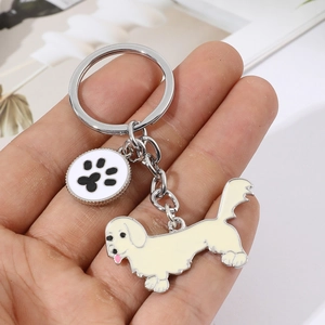 Détail montrant un joli porte-clés chien crème avec un pendentif empreinte de patte noire