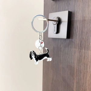 Détail d'un porte-clés Basset Hound en métal avec breloque suspendu à une porte en bois