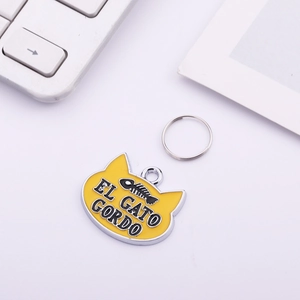 Detail of yellow cat-shaped alloy pet ID tag with fishbone pattern and metal ring