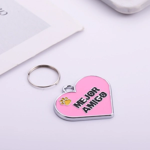 Pink heart-shaped metal pet ID tag with MEJOR AMIGO text and silver hanging ring