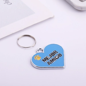 Detail of a heart-shaped blue enamel pet ID tag with a yellow paw print and Mejor Amigo text