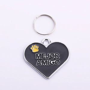 Close-up of heart-shaped pet ID tag with yellow paw print and Mejor Amigo engraving