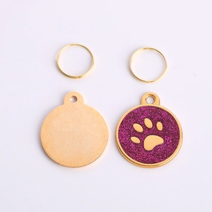 Detail of round gold pet ID tags with purple glitter finish and paw print pattern