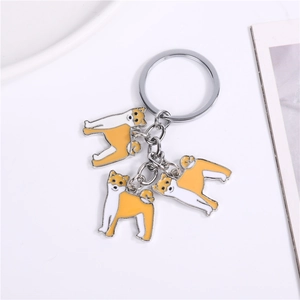 Détail de trois breloques Shiba Inu en émail sur un porte-clés en métal argenté
