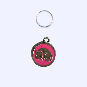 Close-up of a pink enamel round pet tag with a sleeping cat design and a metal ring