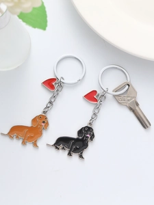 Detailed view of dachshund dog keychains with red heart charms on a white ceramic plate