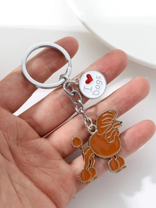 Detail of Poodle keychain with orange enamel and I Love Dogs charm held by hand