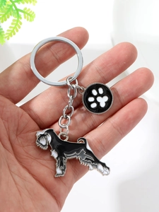 Close-up of schnauzer dog keychain with black enamel puppy and paw print charm on hand