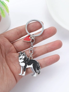 Detail of husky charm keychain with red heart pendant held in hand on white background