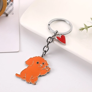 Détail du porte-clés chien orange en métal avec breloque cœur rouge et anneau argenté poli