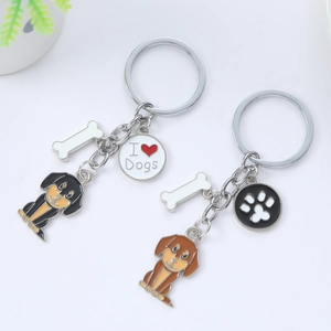 Détail de deux porte-clés chien en émail avec pendentifs os et patte sur fond blanc