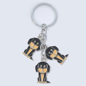 Gros plan de porte-clés mignons pour chiens avec des pendentifs en métal émaillé noir et jaune