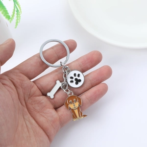 Détail d'un porte-clés chien en métal avec breloques os et patte sur un anneau métallique