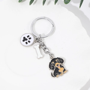 Porte-clés teckel en métal avec breloques os et empreinte de patte sur un plateau blanc
