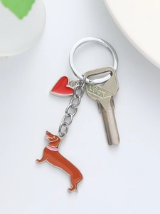 Detail of dachshund keychain with red enamel heart pendant on a white surface