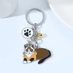 Cartoon ragdoll cat keychain with crown and bells on a white minimalist background