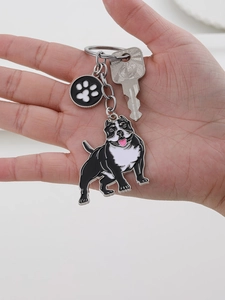 Close-up of alloy enamel pit bull keychain with a black paw print charm in hand