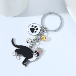 Cartoon black and white cat keychain with crown, paw charm and colorful metal bells